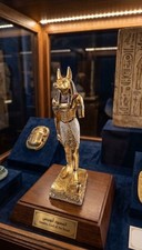 A golden Egyptian Anubis god statue with intricate details on a white picture